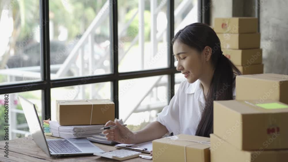 Start an SME, a small business entrepreneur of independent Asian women using laptop with box. cheerful success Woman working on online marketing packaging boxes and delivering SME concepts 4k video Start an SME, a small business entrepreneur of independent Asian women using laptop with box. cheerful success Woman working on online marketing packaging boxes and delivering SME concepts 4k video