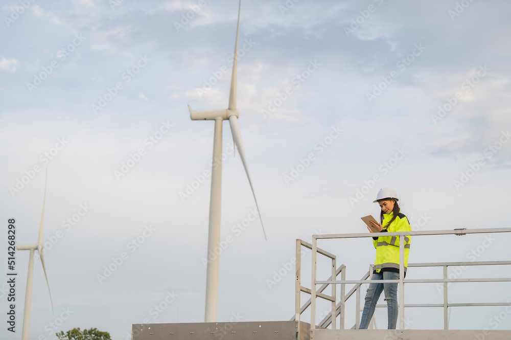 women engineer working and holding the report at wind turbine farm Power Generator Station on mountain,Thailand people women engineer working and holding the report at wind turbine farm Power Generator Station on mountain,Thailand people