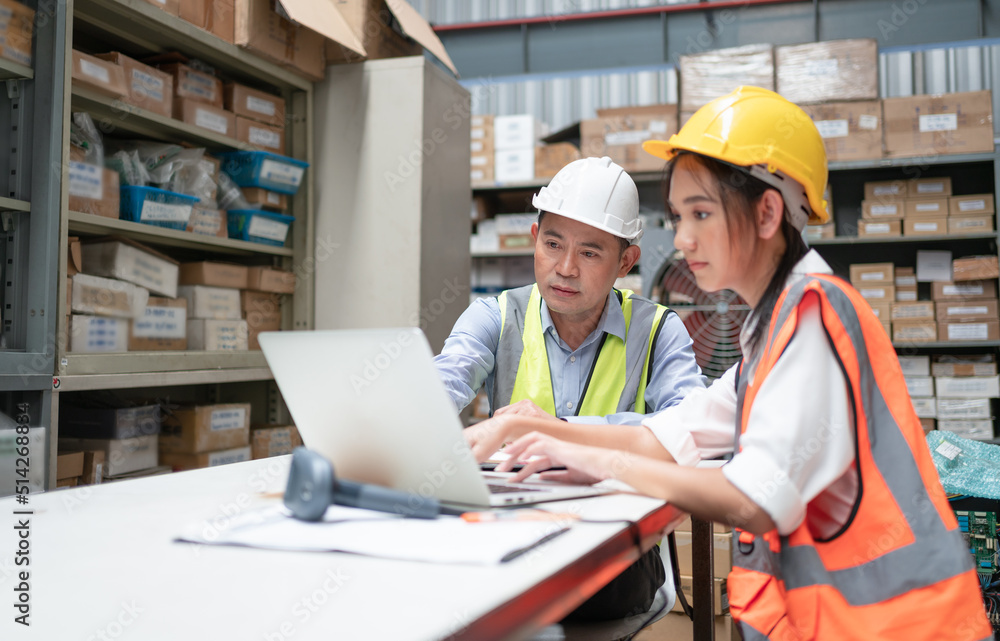 Male inventory manager with female worker looking at laptop checking products in stock inventory at warehouse office Male inventory manager with female worker looking at laptop checking products in stock inventory at warehouse office