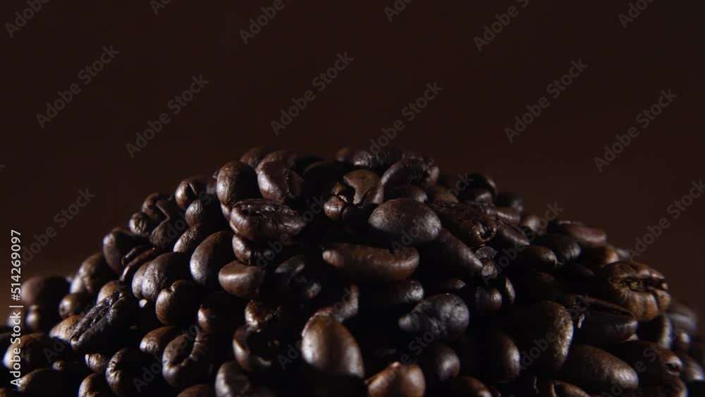 Fragrant coffee beans rotate on a brown background. The smell of aromatic coffee and a charge of vivacity for the whole day concept. Close-up view of a pile of roasted arabica or robusta coffee beans. Fragrant coffee beans rotate on a brown background. The smell of aromatic coffee and a charge of vivacity for the whole day concept. Close-up view of a pile of roasted arabica or robusta coffee beans.