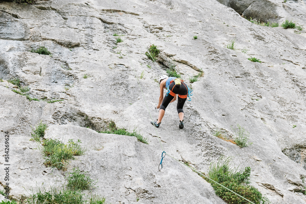 Unrecognizable female climber ascending on cliff in summer Unrecognizable female climber ascending on cliff in summer