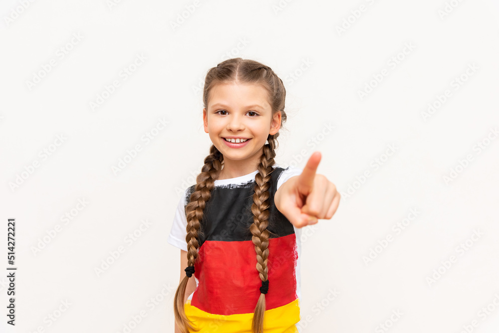 A little girl with a German flag on a T-shirt, with long hair braided in pigtails on a white isolated background. Language courses for children. Space for copying. A little girl with a German flag on a T-shirt, with long hair braided in pigtails on a white isolated background. Language courses for children. Space for copying.
