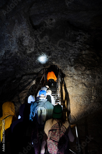 Tourists explore an underground cave, a group of people stuck deep underground, a karst mine, a staircase in a cave at the bottom of a well, a speleo expedition. photo