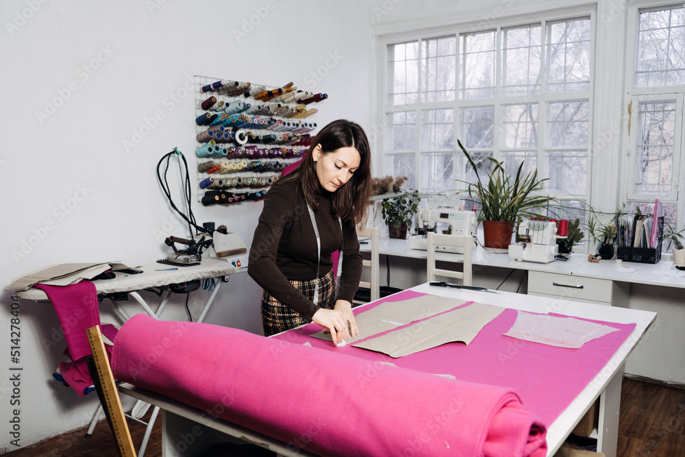 Female fashion designer tailor making sewing patterns at workplace in sewing studio. Female fashion designer tailor making sewing patterns at workplace in sewing studio.