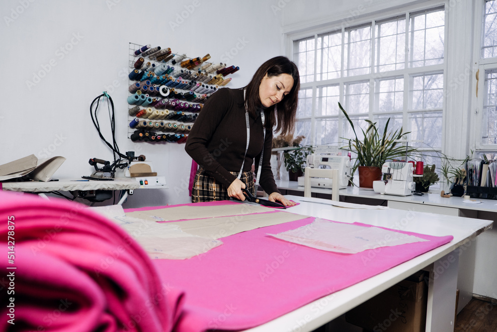Female fashion designer tailor making sewing patterns at workplace in sewing studio. Female fashion designer tailor making sewing patterns at workplace in sewing studio.
