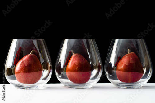 Three little blush pears inside elegant stemless wine glass photo