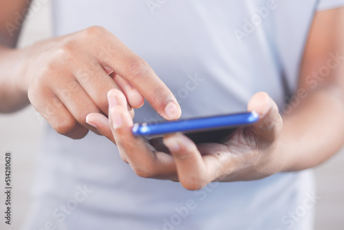 Close up of young man hand using smart phone.