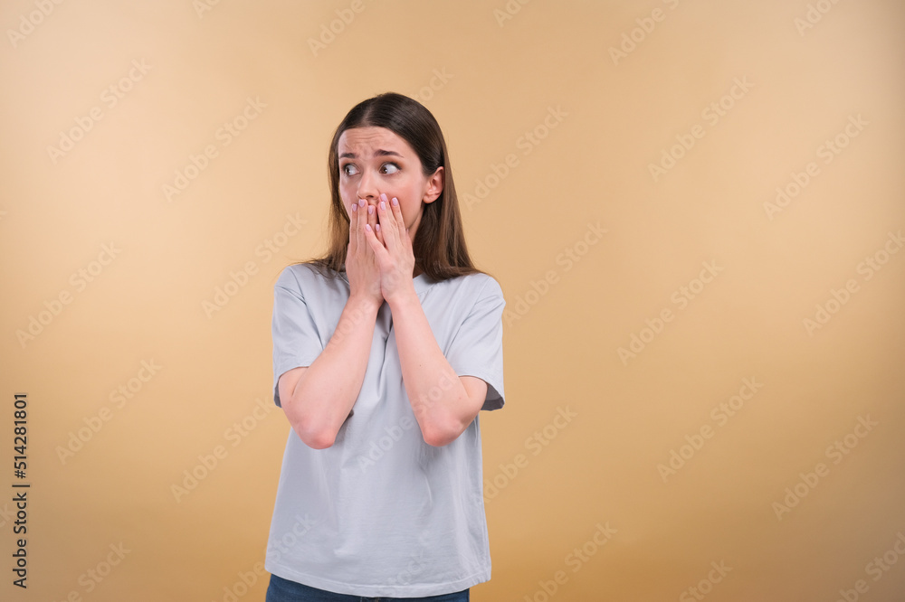 Middle aged woman very scared and afraid, desperate for something, cries of suffering and open eyes, concept of madness on a beige background Middle aged woman very scared and afraid, desperate for something, cries of suffering and open eyes, concept of madness on a beige background