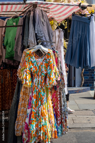 Brightly colored dress and other clothes hanging on rack in Portobello market, London, England
