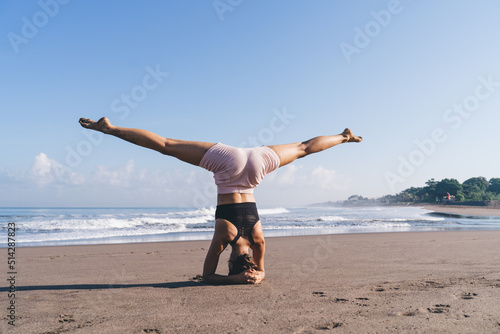 Fototapeta Naklejka Na Ścianę i Meble -  Flexible Caucasian female in active wear exercising during morning yoga feeling vitality and harmony, young slim woman doing asanas for stretching body during athletic practice at seashore