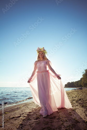 Summer woman portrait in long dress on sea coast against sun