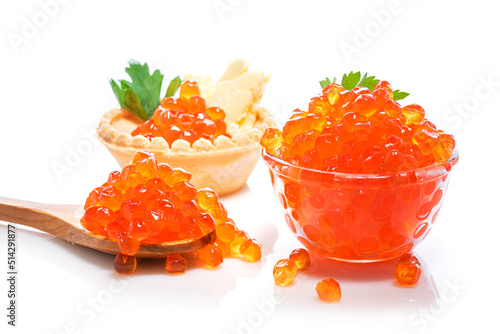 Expensive red caviar in tartlet with butter, in wooden spoon, and small glass bowl with parsley on white background. Caviar in spoon, in tartlet and cup on white background.