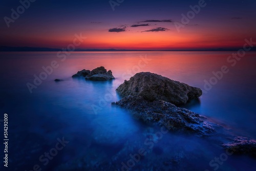 Widok skał oblewanych przez morze o wschodzie słońca przy kolorowym niebie photo