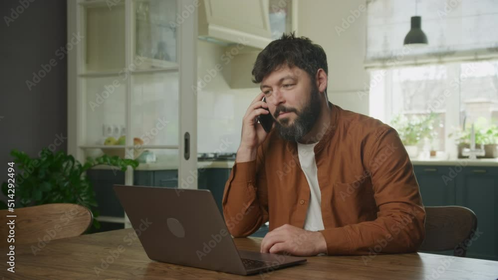 Peforming a sale on his phone in front of a laptop computer. Man recieving good news on phone Peforming a sale on his phone in front of a laptop computer. Man recieving good news on phone