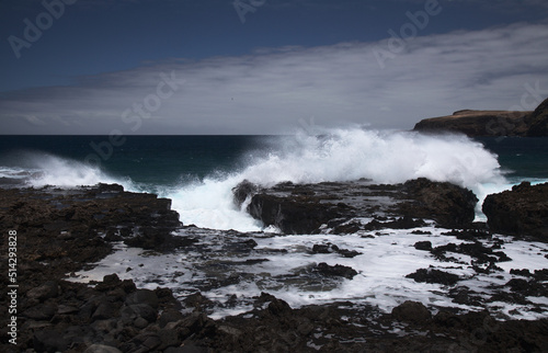 Gran Canaria, north west coast around natural swimming pools Salinas de Agaete, waves breaking against old eroded dark lava platform