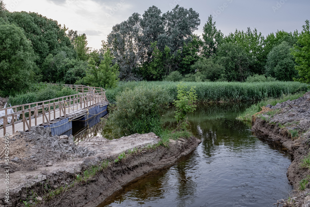 bridge construction site over small river in Latvia. Temporary wooden pedestrian bridge over the river bridge construction site over small river in Latvia. Temporary wooden pedestrian bridge over the river