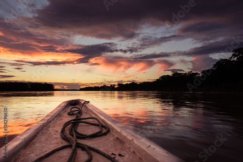 the bow of a canoe with a coiled rope sunset amazon river
