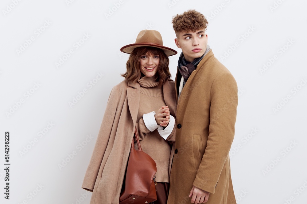 a beautiful couple in love is standing on a white background in autumn clothes and holding hands sweetly, a woman has an autumn hat on her head and a bag in her hand a beautiful couple in love is standing on a white background in autumn clothes and holding hands sweetly, a woman has an autumn hat on her head and a bag in her hand