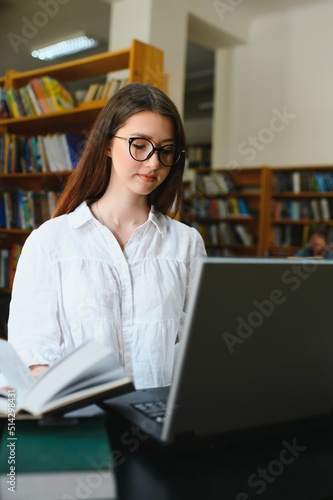 University Library: Beautiful Smart Caucasian Girl uses Laptop, Writes Notes for Paper, Essay, Study for Class Assignment. Focused Students Learning, Studying for College Exams. Side View Portrait © Serhii