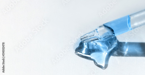Pipette with blue gel, transparent fluid hyaluronic acid. Cosmetics, science and healthcare concept closeup. Dose of retinol. Front view, high angle shot. Beauty product closeup, banner