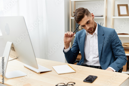 handsome businessman writes in documents at the desk in the office isolated background