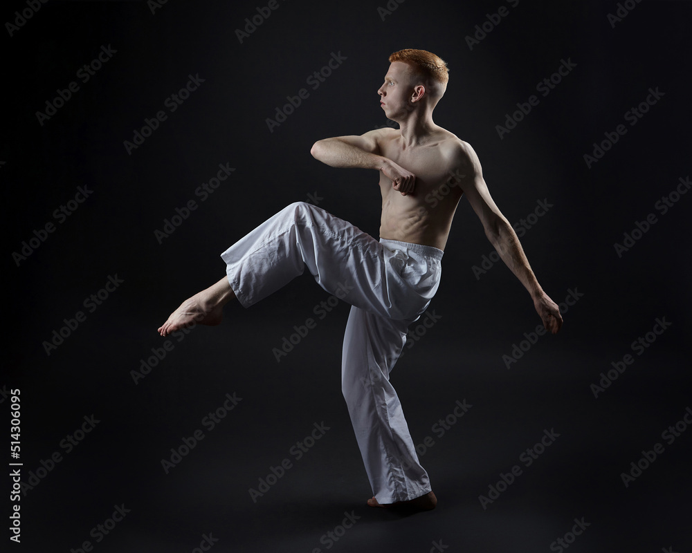 red-haired male dancer demonstrates the choreographic elements of the dance. photo shoot in the studio on a dark background