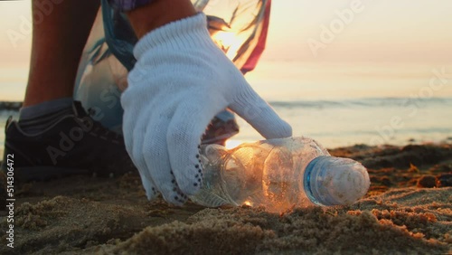 Man in gloves - a volunteer cleans the beach from plastic debris.