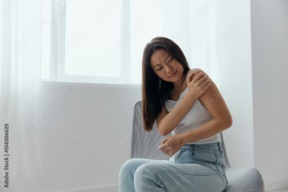 Tormented from shoulder dislocation fractures pain after lifting weights in the wrong position tanned beautiful young Asian woman touching painful shoulder at home interior living room. Cool offer Tormented from shoulder dislocation fractures pain after lifting weights in the wrong position tanned beautiful young Asian woman touching painful shoulder at home interior living room. Cool offer