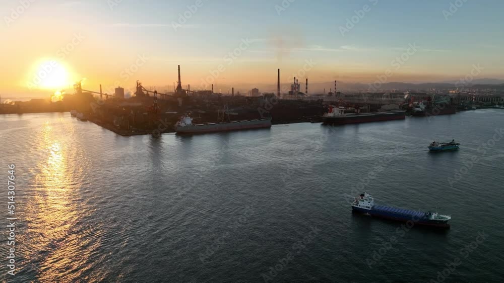 Slow pullback on ships and industrial factory with smokestacks at sunset Slow pullback on ships and industrial factory with smokestacks at sunset