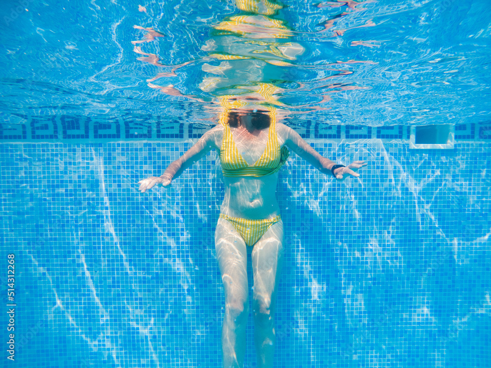 woman in yellow swimming suit in clear blue water in pool