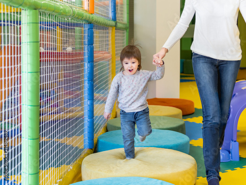 Toddler plays with his mother or babysitter. Physical development for little children. Interior of kindergarten or nursery. photo