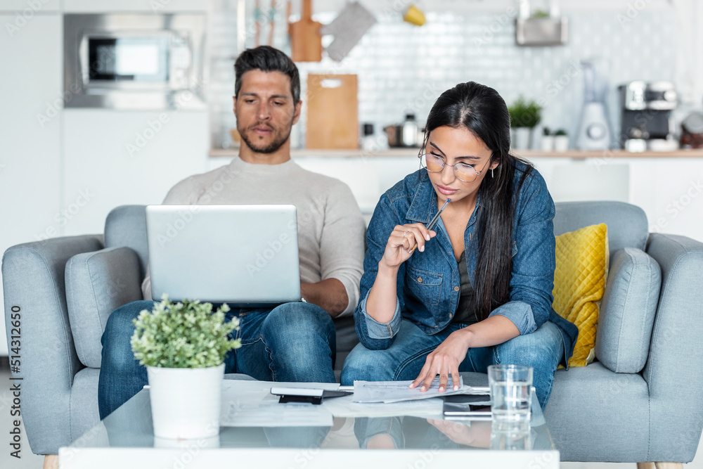 Exhausted couple using their laptop to consulting some invoices and documents while sitting on the couch at home. Exhausted couple using their laptop to consulting some invoices and documents while sitting on the couch at home.