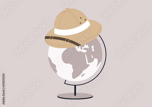 A colonial hunter cork hat, a symbol of colonialism and usurpation sitting on top of a round Globe on a metal stand