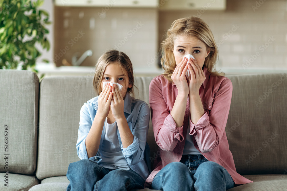 Sad caucasian mother and daughter with a cold are sitting at home on ...