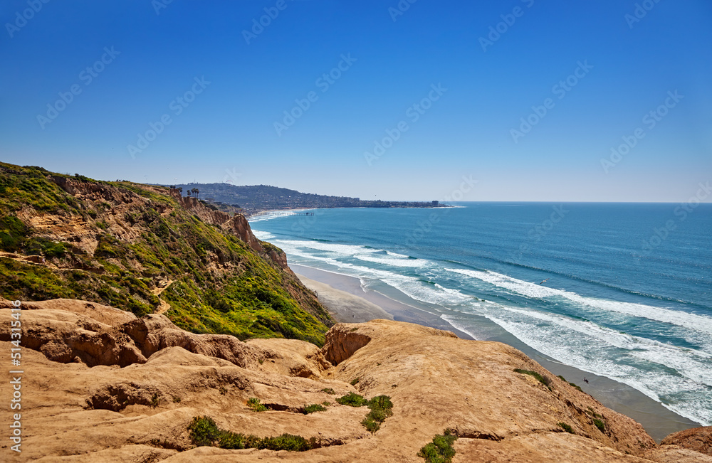 Steep, eroded cliffs with a zigzag path to Black's Beach, California. Scripps Pier and La Jolla Cove in the distance Steep, eroded cliffs with a zigzag path to Black's Beach, California. Scripps Pier and La Jolla Cove in the distance
