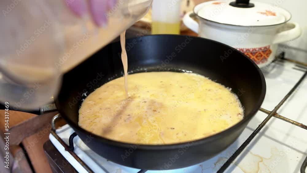 The girl pours the scrambled omelet into the frying pan for frying it. Shooting kurpno in slow motion The girl pours the scrambled omelet into the frying pan for frying it. Shooting kurpno in slow motion