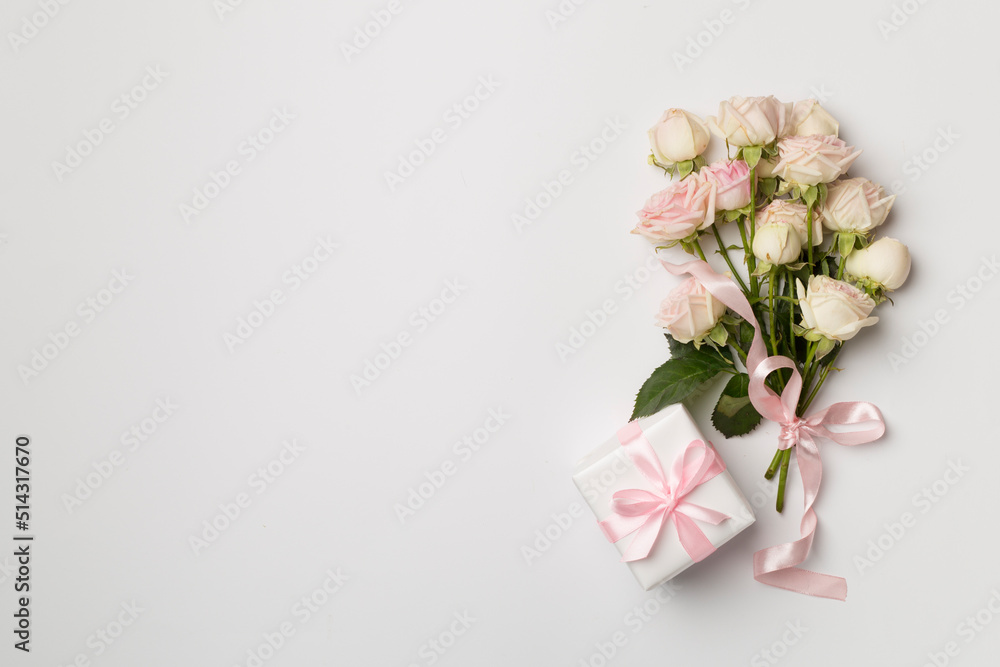 Gift box and rose flowers on white background, top view