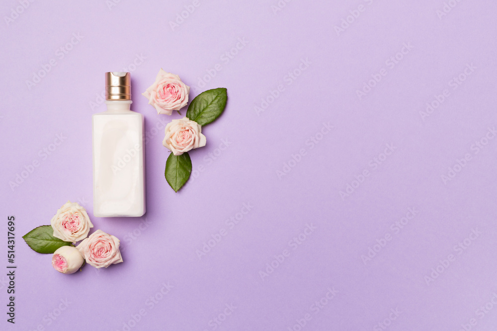 Cosmetic bottle with rose flower on color background, top view Cosmetic bottle with rose flower on color background, top view