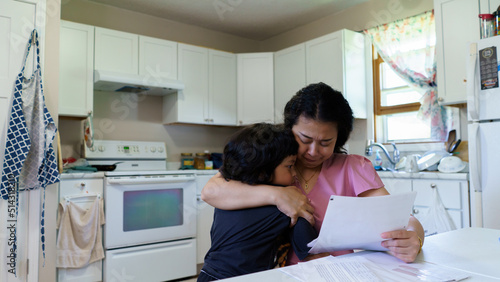 Sad daughter hugging his mother. She is young asian woman unemployed reading paper pay bills feeling frustrated of getting eviction letter or bank debt notification, concept unemployed pay bills. photo