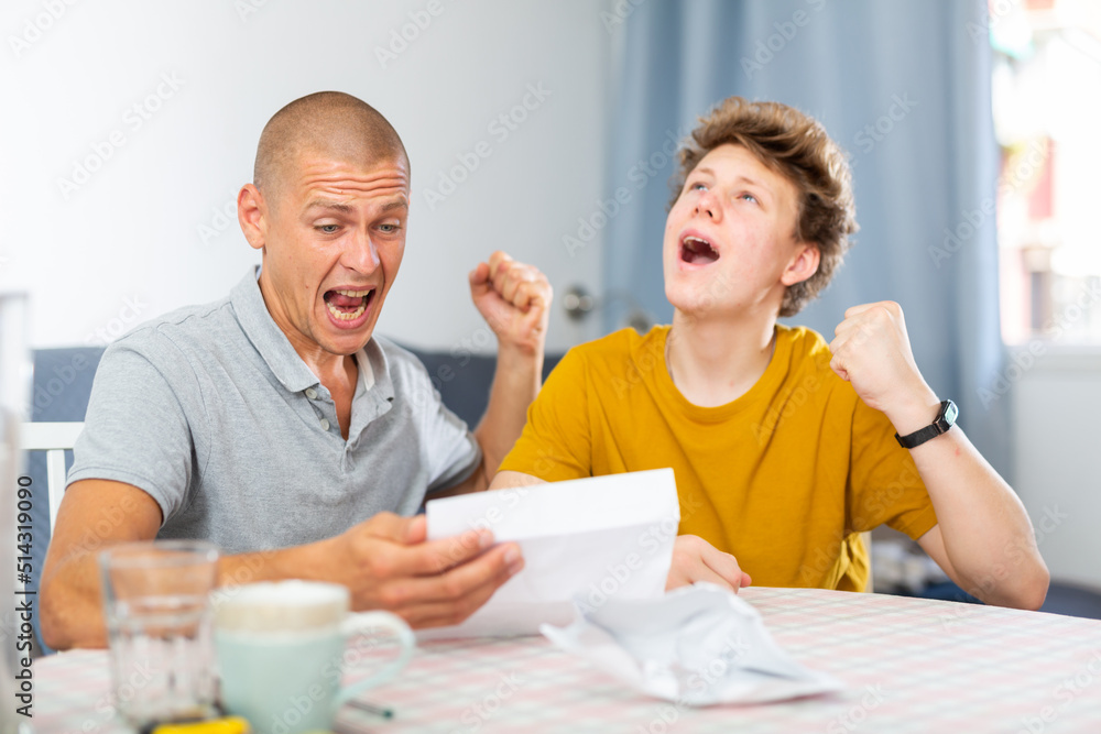 Joyful father and son cheering after reading a letter from college