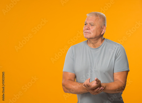 an elderly man measures his pulse. the older man feels bad and measures his pulse. The man is concerned about his health. on a yellow background isolated