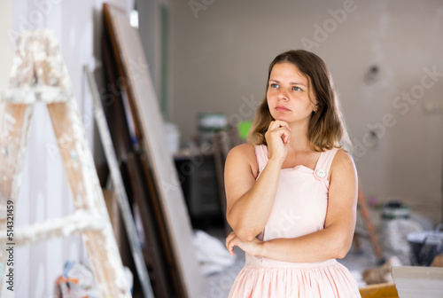 Female owner of the cottage in a beige dress checks the quality of the room renovation
