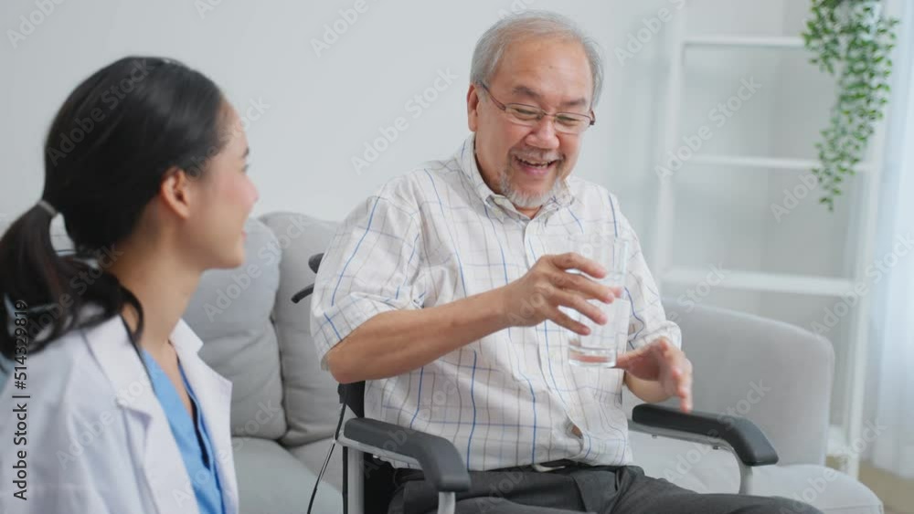 Asian caregiver serve water to senior male while sitting on wheelchair Asian caregiver serve water to senior male while sitting on wheelchair