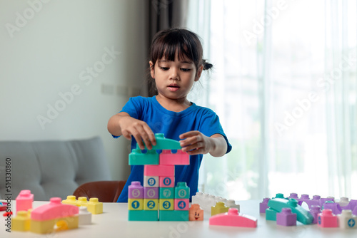 Little child girl playing colorful blocks