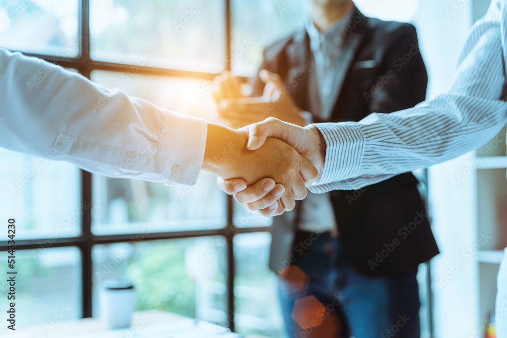 Two business people shake hands after a business deal is reached In the office area, close up.