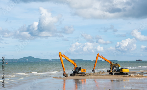 yellow and orange excavator machinery or Loader Vehicle with copy space. Drilling holes on the beach sea cliff during shore beach improvement