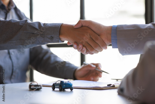 Car rental service sales give the car key concept. Close up view Hand of agent handshake to the customer after signing rental contract form.