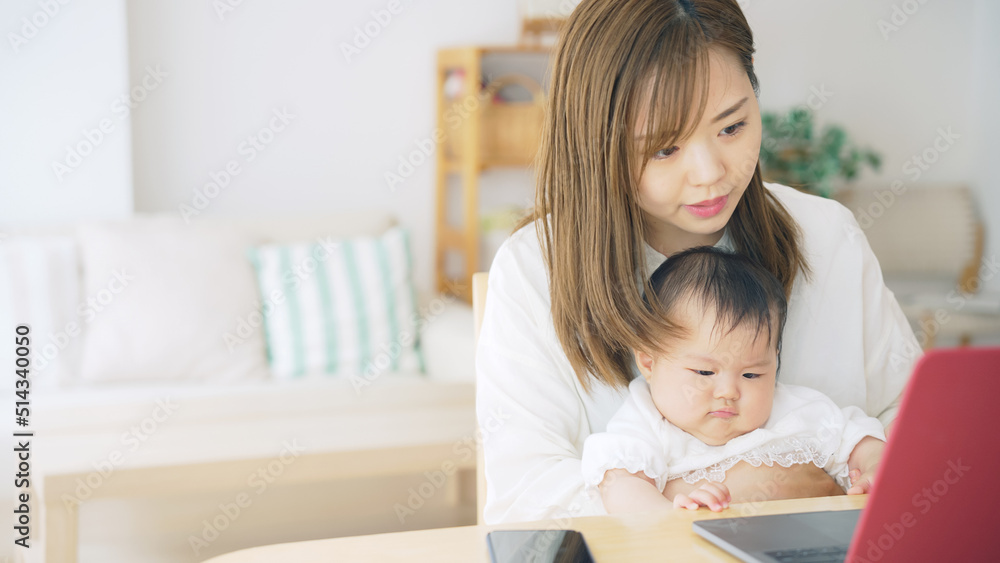 赤ちゃんを抱っこしながら自宅で仕事する女性 子育てしながらの在宅勤務 赤ちゃんを抱っこしながら自宅で仕事する女性 子育てしながらの在宅勤務