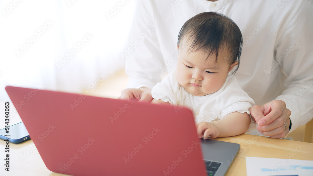 赤ちゃんを抱っこしながら自宅で仕事する男性 赤ちゃんを抱っこしながら自宅で仕事する男性