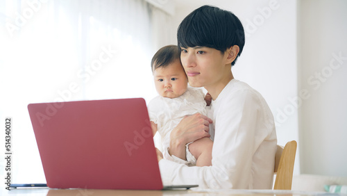 赤ちゃんを抱っこしながら自宅で仕事する男性